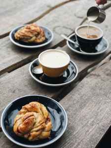 two brown and black ceramic teacups filled on black saucers