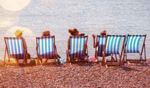four people on lounge chairs near the beach